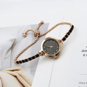 Women's gold quartz watch with minimalist black dial and gemstone bracelet strap