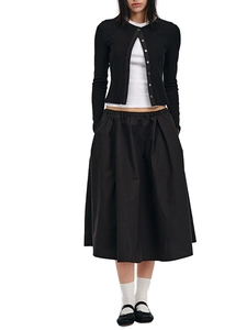 Full view of black knit cardigan, white top, and midi skirt set on minimalist model