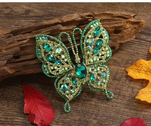 Vue détaillée d'une broche papillon en cristal vert avec détails dorés sur bois