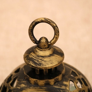 Macro shot of antique gold metal lantern top with intricate cutouts and round hanging ring
