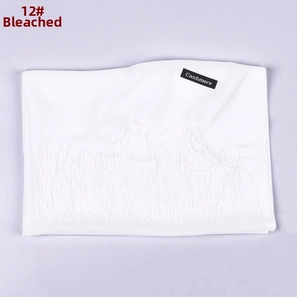 Detail of bleached white cashmere scarf with fringe trim and premium black brand label