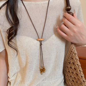 Close-up of a long wax rope necklace featuring wooden beads and silver metallic accents