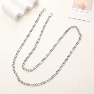 Detail of silver metal crossbody chain strap with lobster clasps on cream background