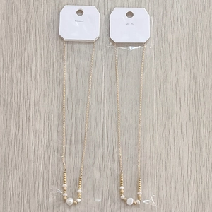 Detail of beaded gold chain necklace set with freshwater pearls on white card