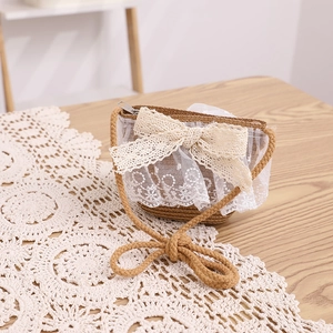 Detail of child straw bag with white lace bow and zipper on a rustic wooden table