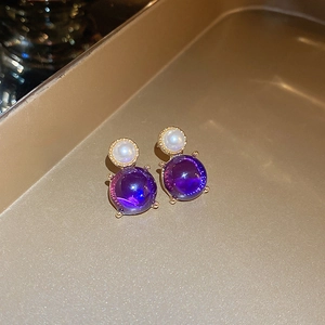Gros plan de boucles d'oreilles vintage dorées avec perles blanches et pierres violettes
