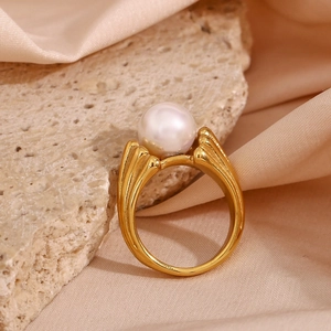 Macro shot of gold-plated leaf ring with pearl on silk background and stone