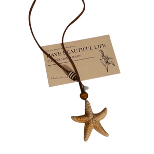 Starfish pendant necklace with wooden beads and brown cord on minimalist white background
