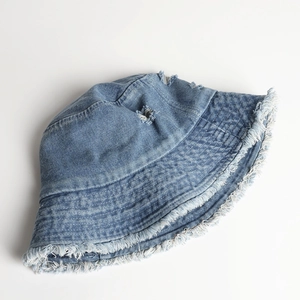 Detail of light blue denim bucket hat with frayed edges and distressed ripped finish