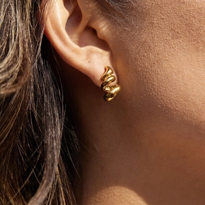 Boucles d'oreilles spirales élégantes en acier plaqué or 18 carats sur un modèle