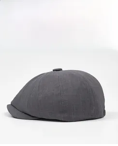 Side view detail of a dark grey octagonal newsboy hat with twill fabric texture
