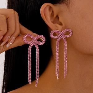 Élégantes boucles d'oreilles nœud à pampilles en strass roses portées par un mannequin chic