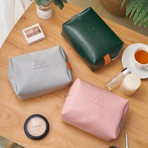 Three multi-colored PU leather makeup bags on a wooden desk with decorative items