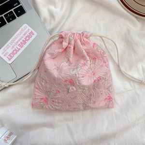 Pink jacquard drawstring bag with rabbit pattern next to a laptop on a white cloth