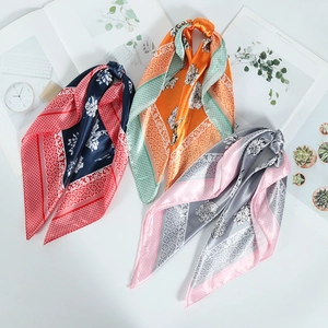 Flat lay of square silk scarves with floral patterns in navy red and orange green styles