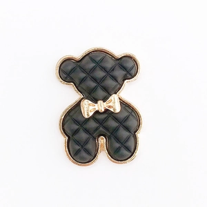 Detailed view of a black quilted teddy bear alloy charm with gold metal accents