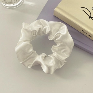 Close-up of white satin scrunchie with pearl-like luster in a French style aesthetic