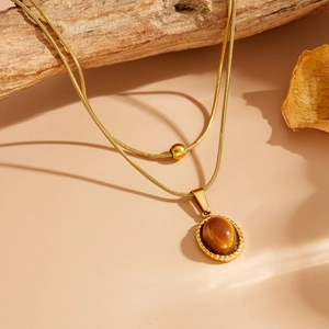 Détail du collier vintage double chaîne serpent dorée avec pendentif en pierre œil-de-chat