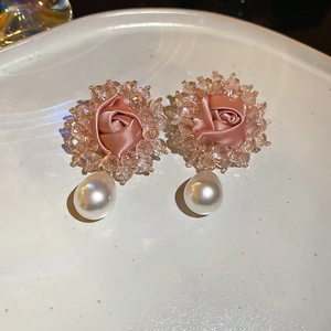 Macro detail of fabric rose earrings with crystal beads and a white pearl drop