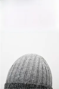 Detail of gray knitted beanie with ribbed texture and warm fleece lining for winter