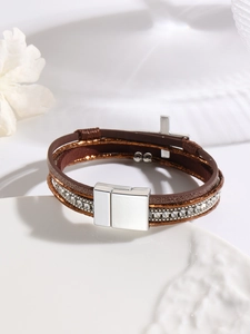 Macro detail of Bohemian multilayer leather bracelet with silver cross and crystal charms