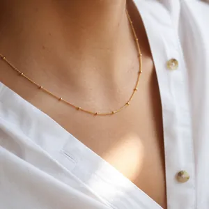 Elegant close-up view of minimalist gold stainless steel beaded chain necklace on neck