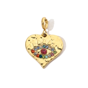 Macro shot of gold heart-shaped evil eye pendant with central ruby and colorful rhinestones