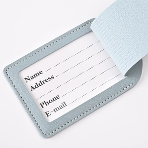 Close-up of light blue PU leather luggage tag with white personal information card