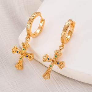 Close-up of golden hoop earrings with textured cross pendants and colorful gemstones