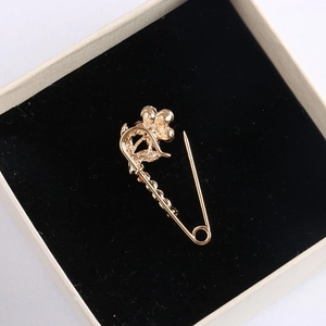 Elegant gold flower brooch on black velvet padding within a beige jewelry gift box