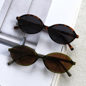 Close-up of tortoise and olive green oval polarized sunglasses on magazine pages