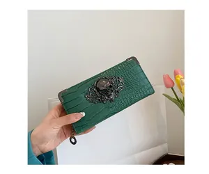 Detail of green crocodile textured clutch featuring a metal skull and corner protectors