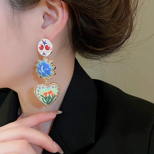 Close-up of geometric enamel heart earrings showing colorful sun and floral patterns