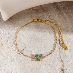 Detailed macro view of gold-plated butterfly bracelet with blue zircons on stone background