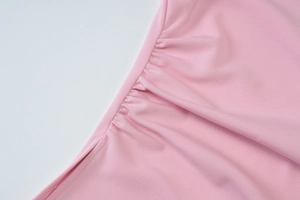 Gros plan détaillé montrant la texture du tricot rose et les détails plissés élégants