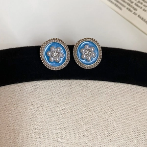 Macro shot of vintage round blue enamel earrings with pearls and gold floral trim