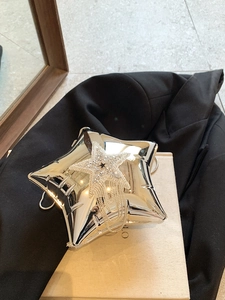 Detailed view of silver star-shaped clutch bag with rhinestone star and fringe chains