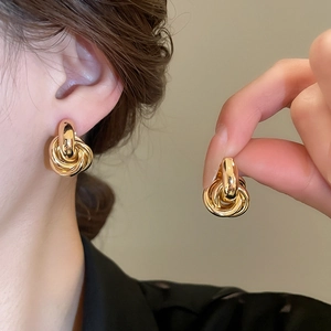 Nahaufnahme der goldenen mehrlagigen geknoteten Metallohrringe mit glänzendem Finish