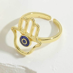 Detailed macro view of gold-plated Hamsa Hand ring with a colorful blue Evil Eye charm