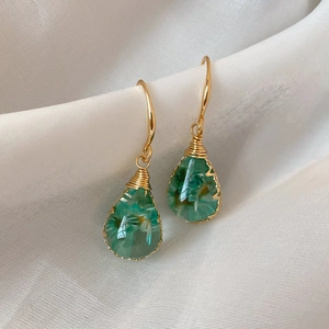 Close-up of handmade green dry flower resin teardrop earrings with gold hooks