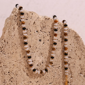 Detail of beaded necklace with tiger eye stones and gold accents on a rock surface