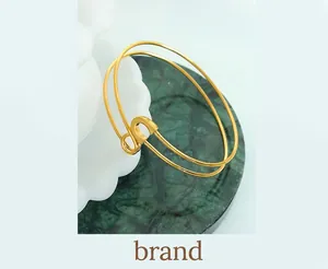 Detail of double-layer gold bangle with letter S charm on a marble plate