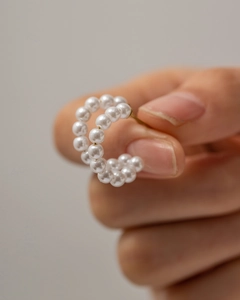 Close-up of C-shaped hoop earring featuring large white pearls and stainless steel pin