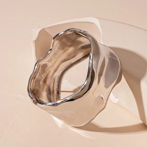 Detail of silver irregular cuff bracelet with a liquid metal texture and mirror finish