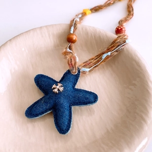 Dettaglio macro del ciondolo in denim a forma di stella con perline e corda intrecciata