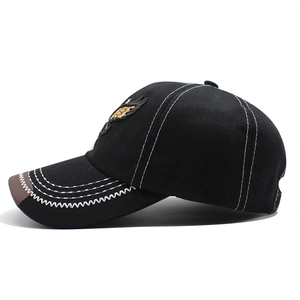Detail of black baseball cap featuring white contrast stitching and eagle embroidery