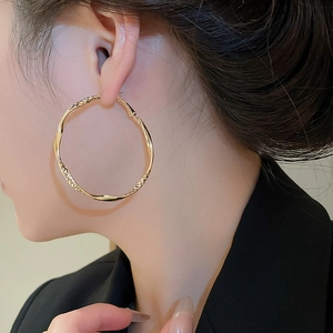 Nahaufnahme eines Models mit großen goldenen geometrischen gedrehten Creolen mit Metallglanz