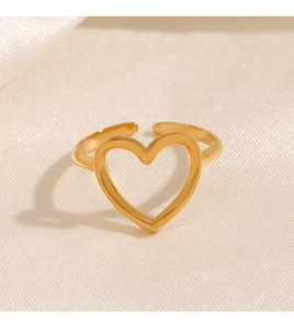 Macro detail of gold-plated hollow heart ring on white silk fabric background