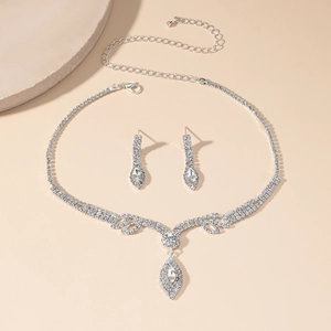 Sparkling rhinestone bridal necklace and earrings set with silver-tone base on a stone decor