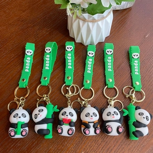 Set of six cute 3D silicone panda keychains with green wrist straps on wooden background